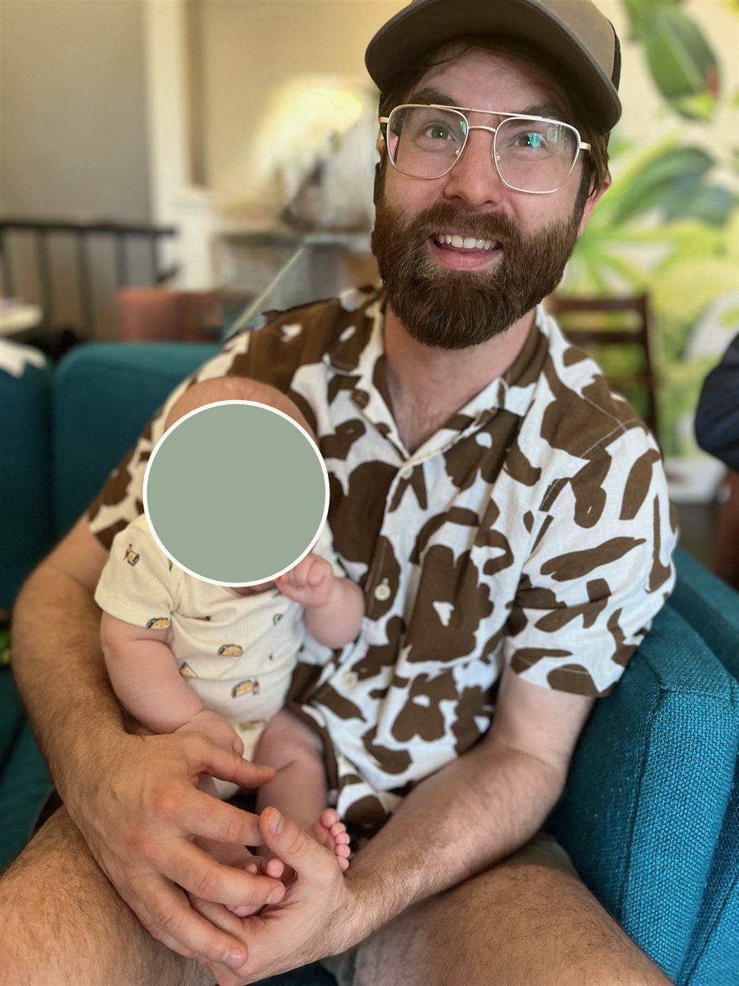Laurence smiling, holding a new baby in the family